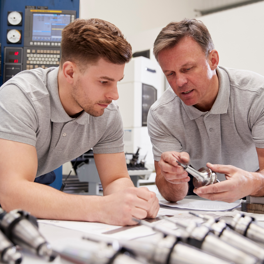 Two engineers discussing a machine's component.