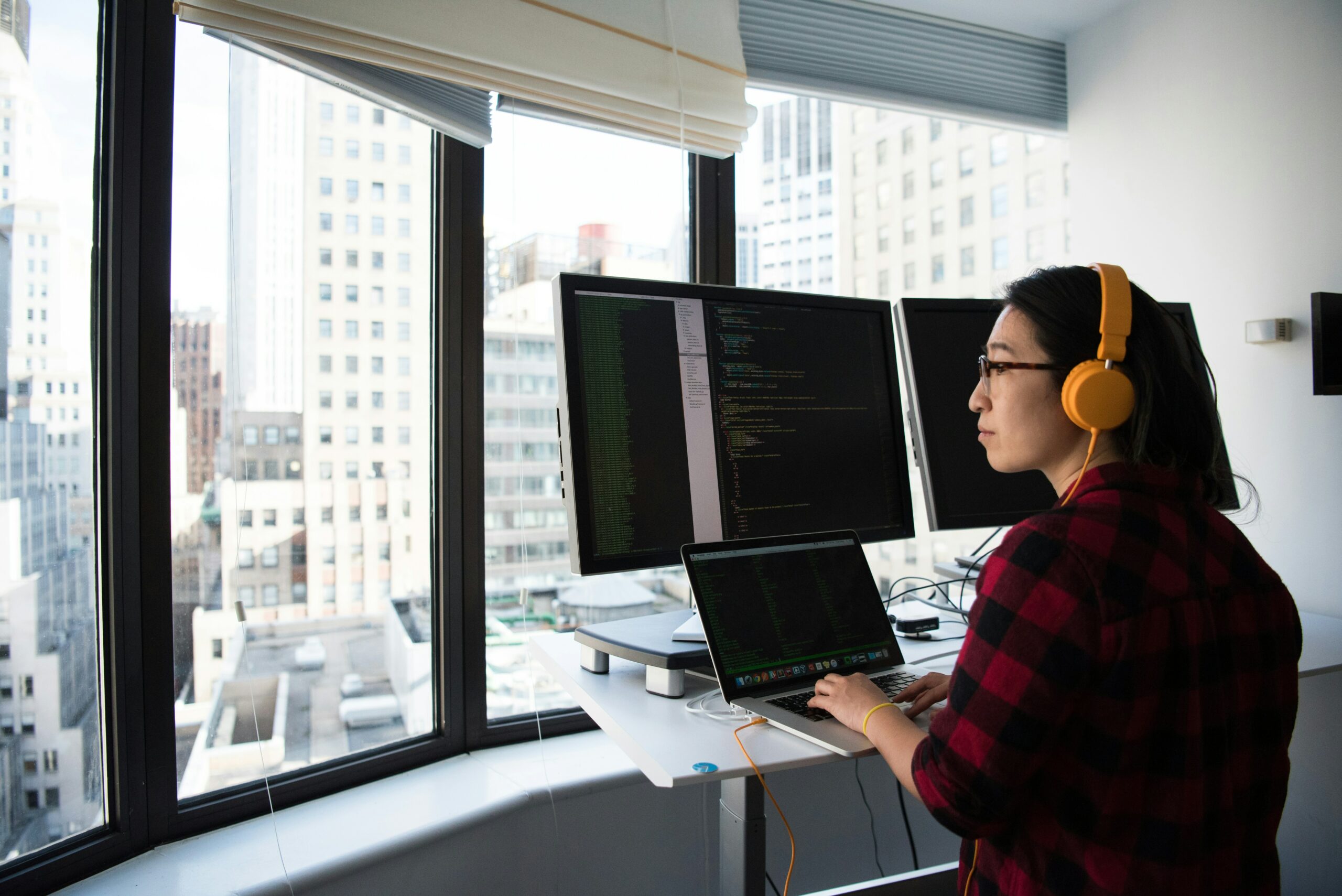 Software engineer coding in front of a skyline view.