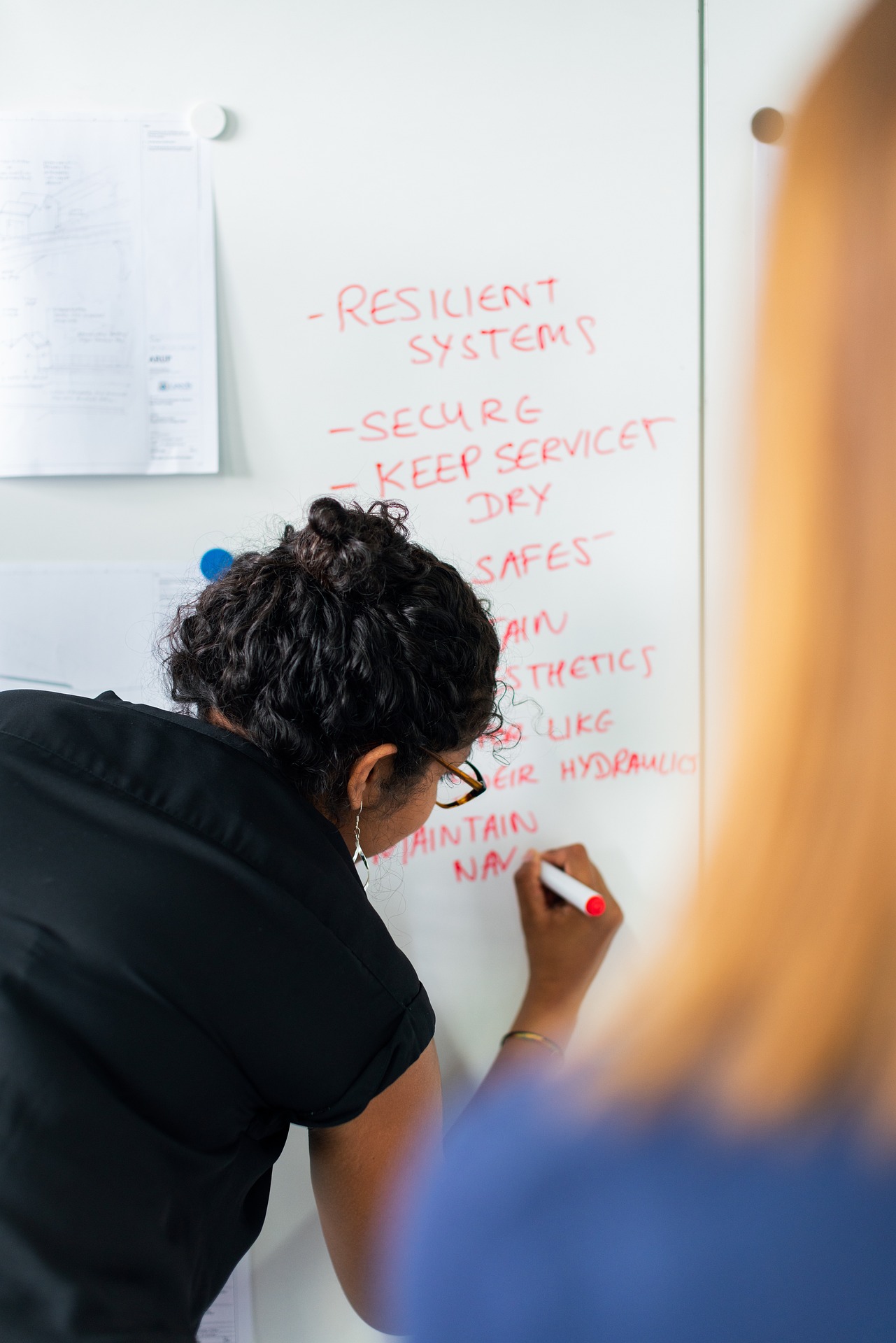 Systems engineer listing down system components on a whiteboard.