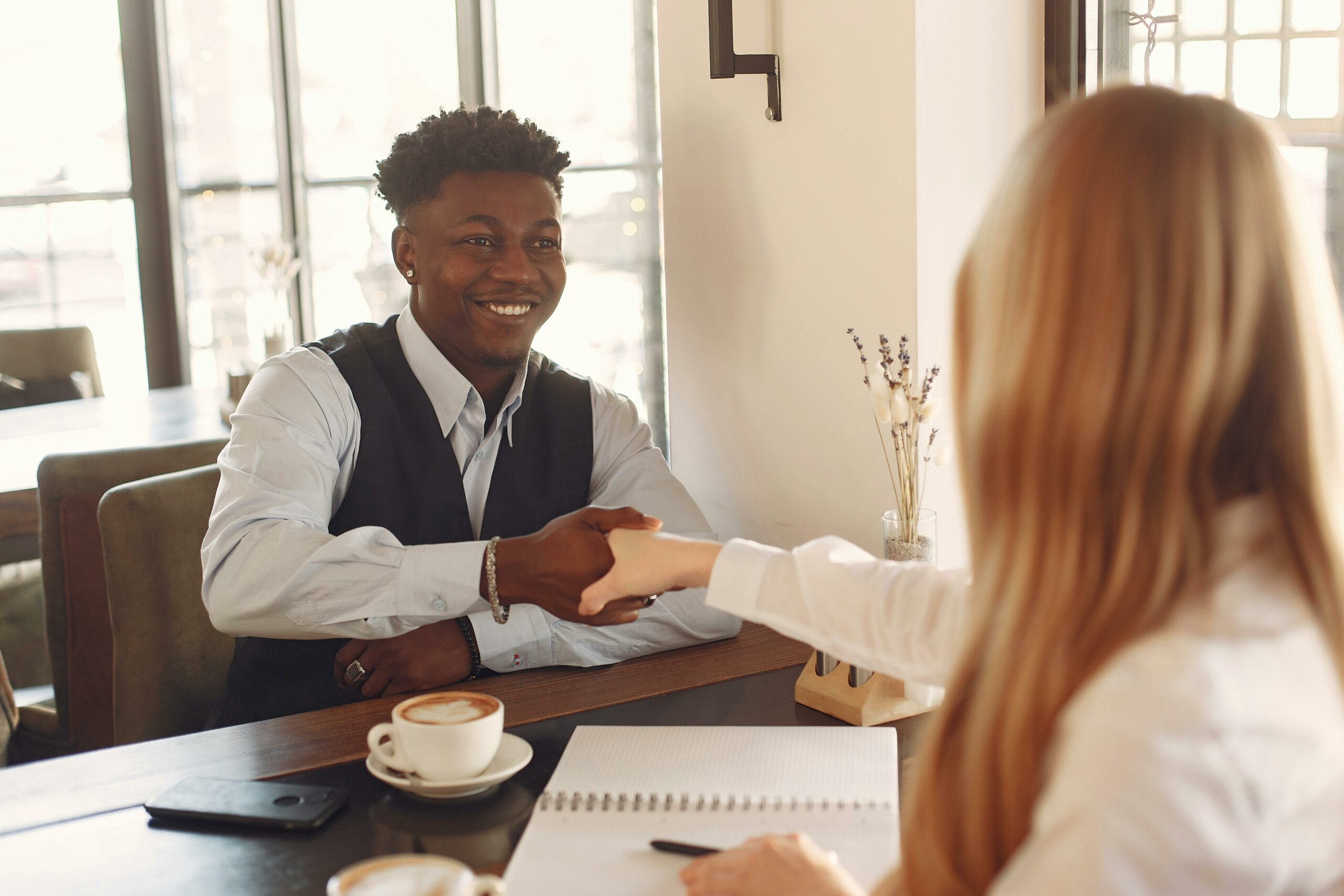 Two professionals shaking hands across a table. 