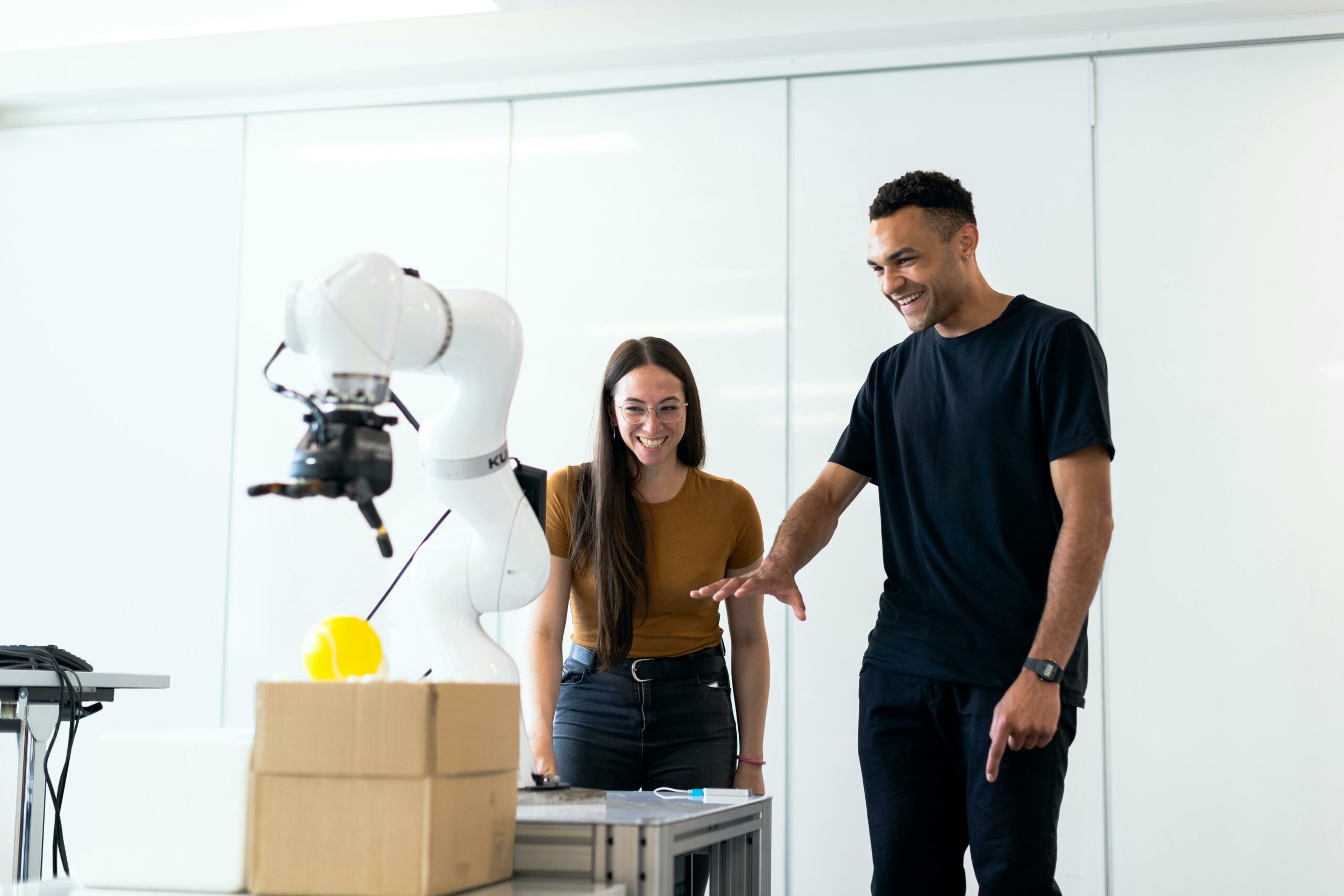 Two robotics engineers testing a mechanical robot arm.