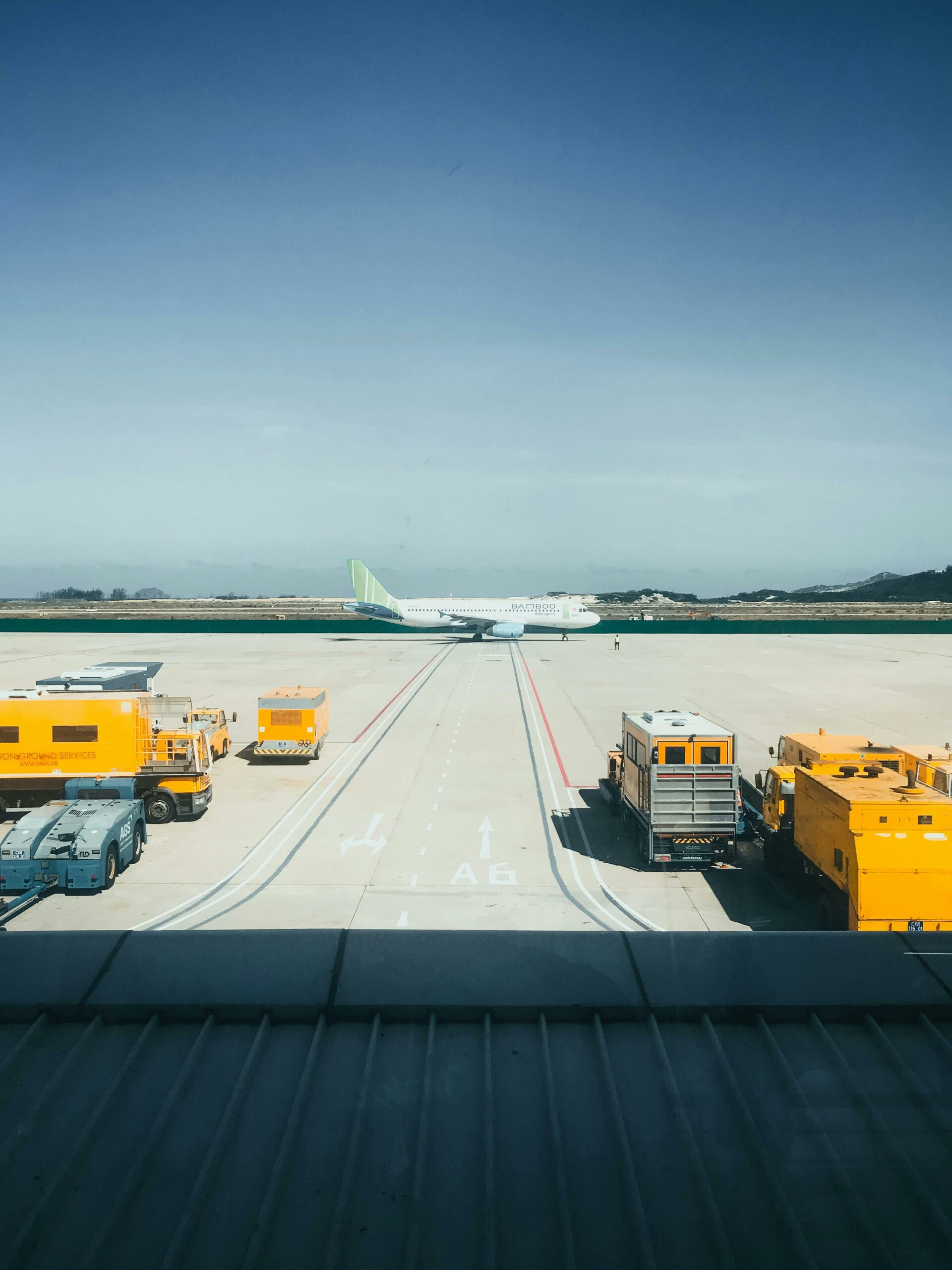 A plane between yellow trucks and work vehicles on a runway.